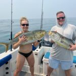 Two tourists holding their catches after a fun day of fishing with Belize Reef Charters.