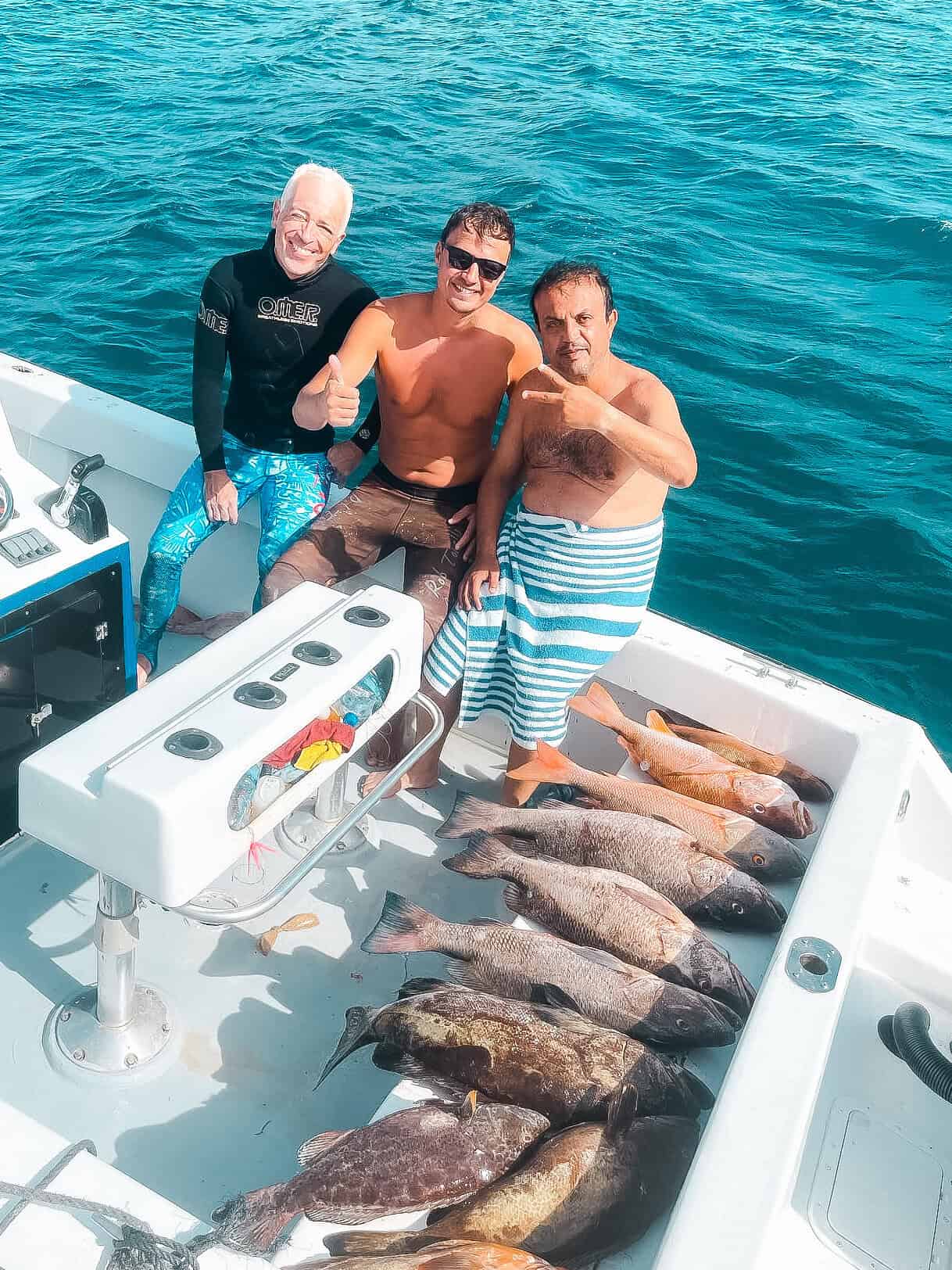Colorful fishing trip with excited anglers showing off their catch on a Belize Reef Charters boat. Grilled fish and ocean scenery highlight Belize's prime deep-sea fishing experiences.
