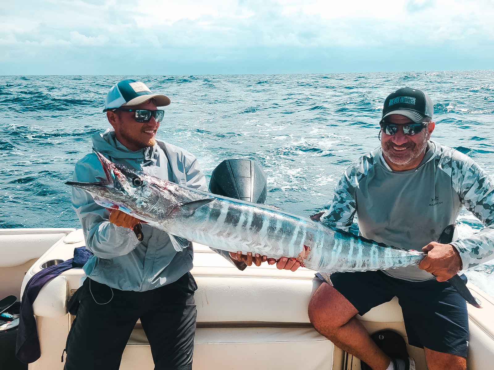 Guides and guest holding Wahoo on a deep-sea fishing trip in Belize
