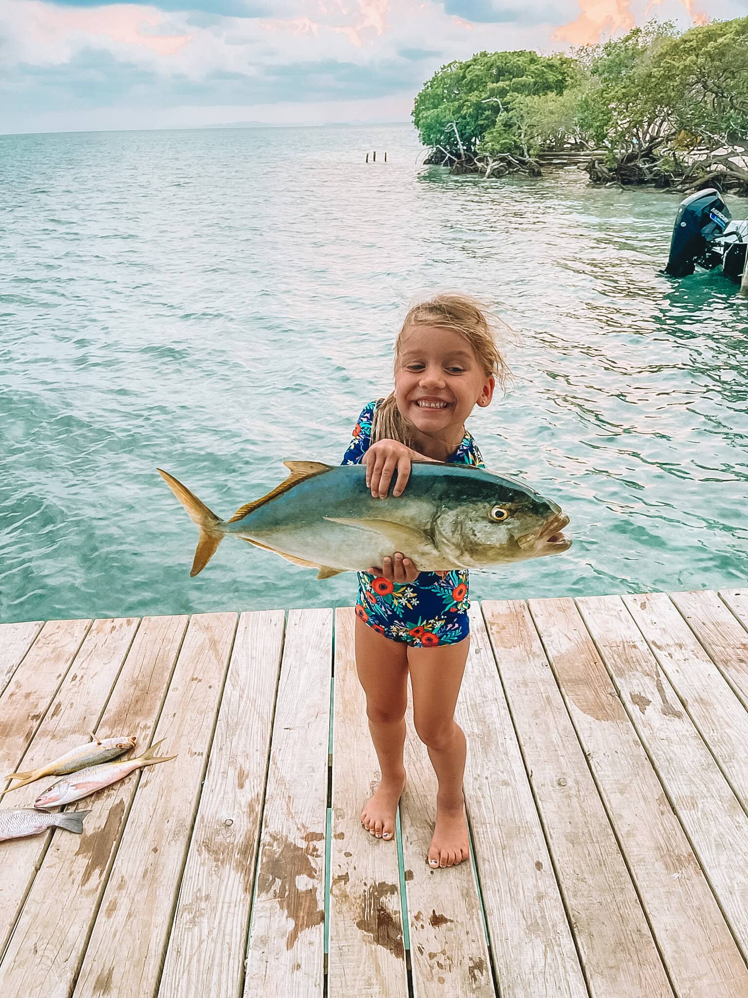 Bridge the gap between nature and adventure with a joyful young girl holding a large fish after a snorkeling trip in Belize. Experience vibrant marine life with Belize Reef Charters for unforgettable ocean excursions.