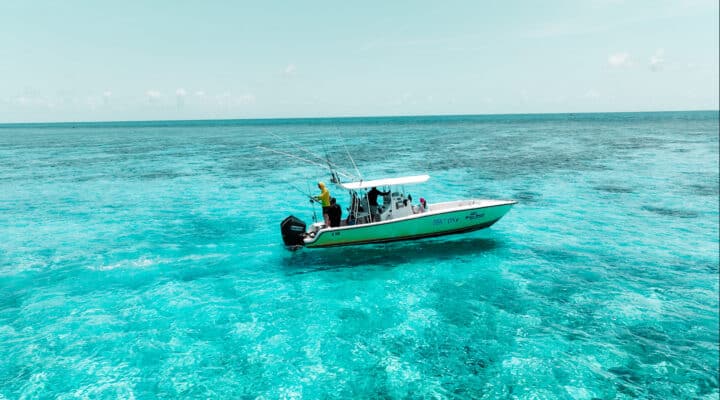 Colorful Belize Reef Charters boat cruising over clear turquoise Caribbean waters, perfect for snorkeling, scuba diving, and fishing adventures in Belize's vibrant coral reef environment.