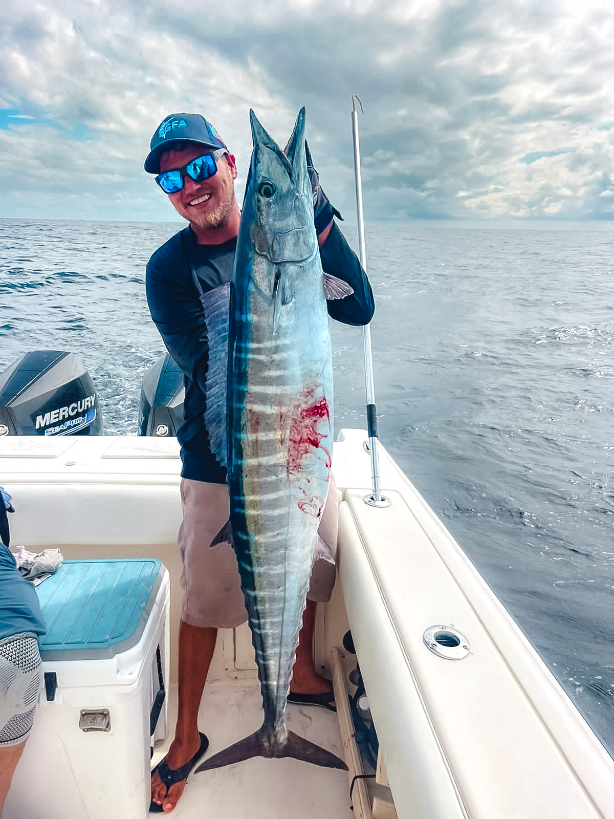 belize fishing guide holding a wahoo from a deep sea fishing tour in belize.