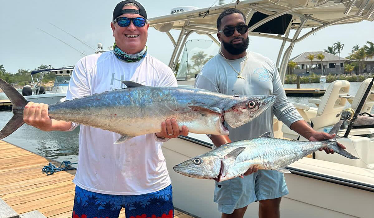 Guests on a fishing charter in belize, holding kingfish