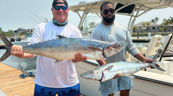 Guests on a fishing charter in belize, holding kingfish