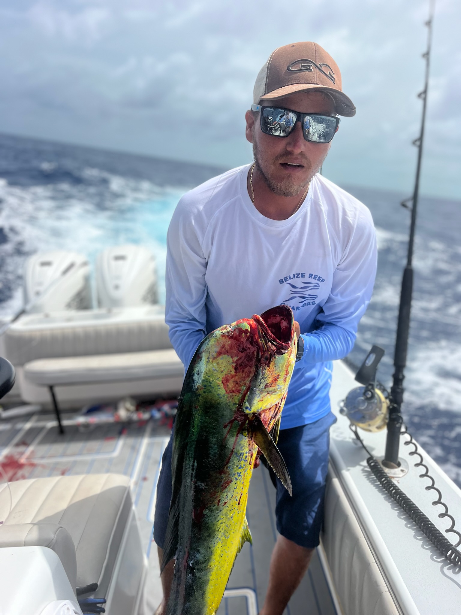 Fishing guide holding a large mahi mahi (dorado) caught in Belize during a deep sea fishing charter.