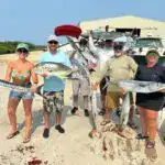 Vibrant group of anglers displaying large catches of fish on Belize Reef Charters, showcasing an exciting day of deep-sea fishing with Belize Reef Charters in Belize.