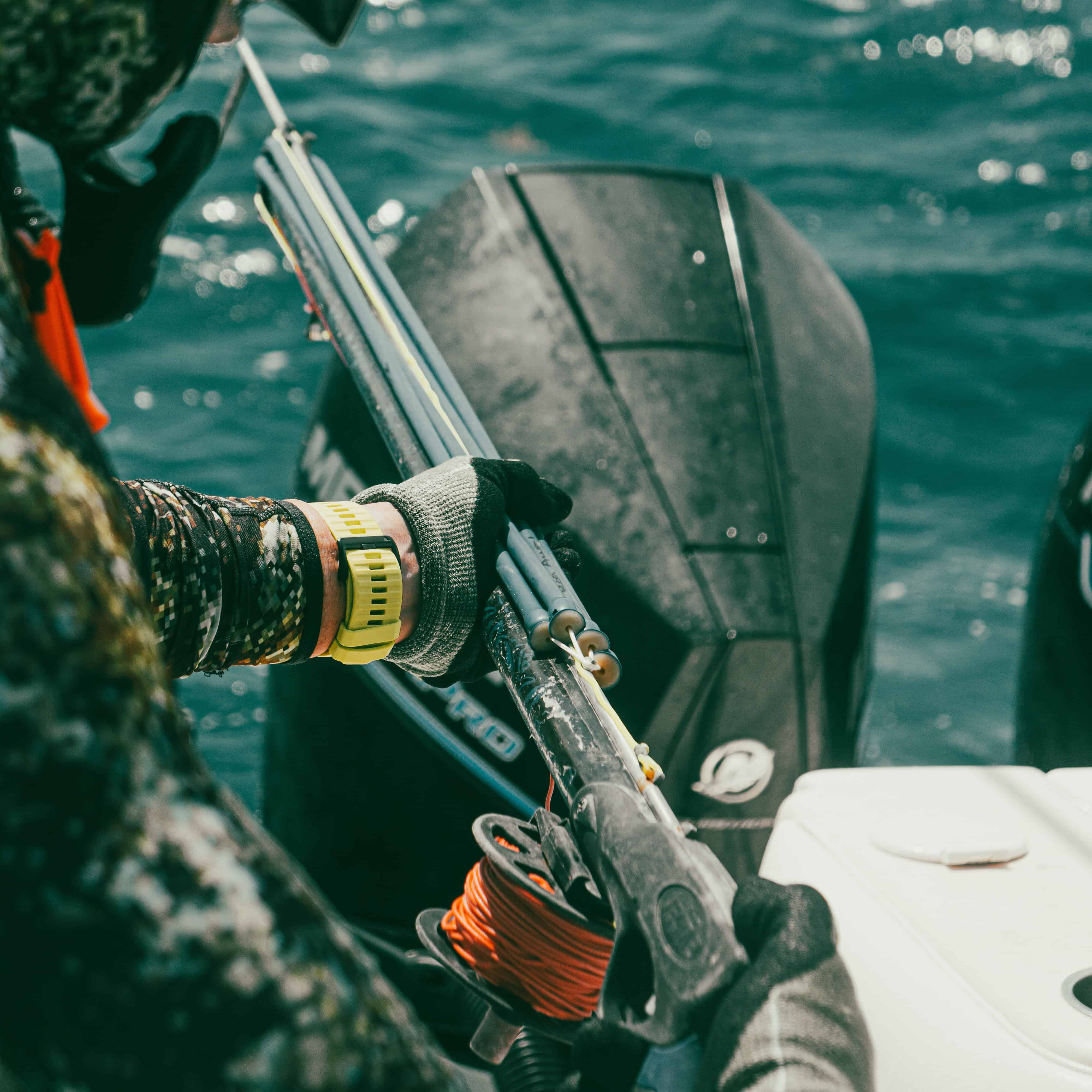 Fisherman preparing for reef fishing on Belize Reef Charters boat with fishing gear and boat motor in clear ocean water.