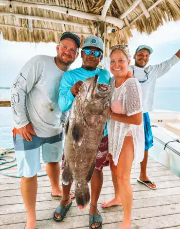 Large group of people holding a big fish after a successful Belize reef fishing trip, showcasing the excitement of Belize Reef Charters and offshore fishing adventures.