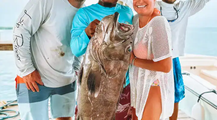 Large group of people holding a big fish after a successful Belize reef fishing trip, showcasing the excitement of Belize Reef Charters and offshore fishing adventures.