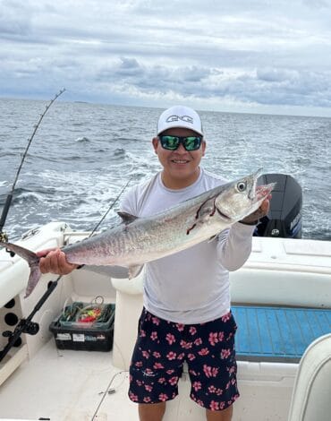 Calm Blue Waters Belize Reef Charters, man holding a large fish on a boat during deep-sea fishing adventure. Perfect for fishing vacation, Belize marine life, and reef fishing excursions.