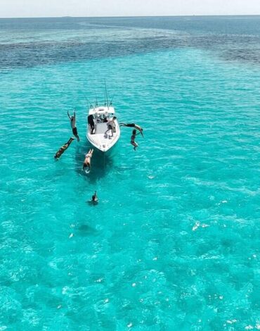 Vibrant Belize reef with people enjoying snorkeling and boat tours in crystal-clear turquoise waters. Ideal for adventurous travelers seeking Belize Reef Charters experiences.