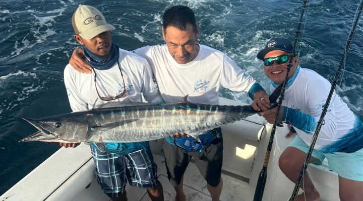 Guests holding a freshly caught wahoo on a deep sea fishing charter in Belize